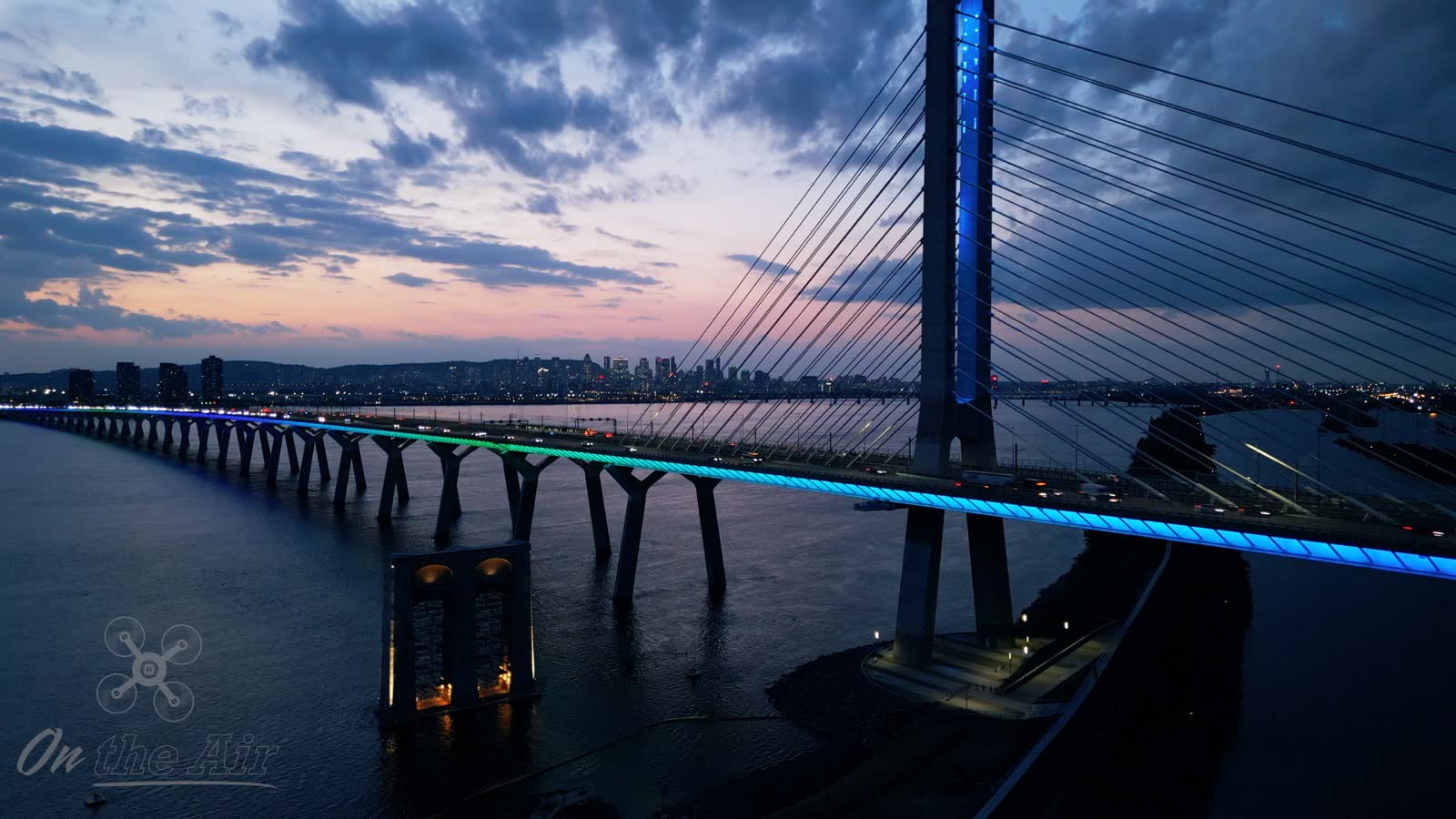 Pont Samuel-De Champlain illuminé au crépuscule, avec le centre-ville de Montréal en arrière-plan